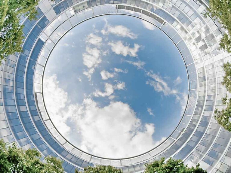 Sky and trees seen through a circular domed glass ceiling