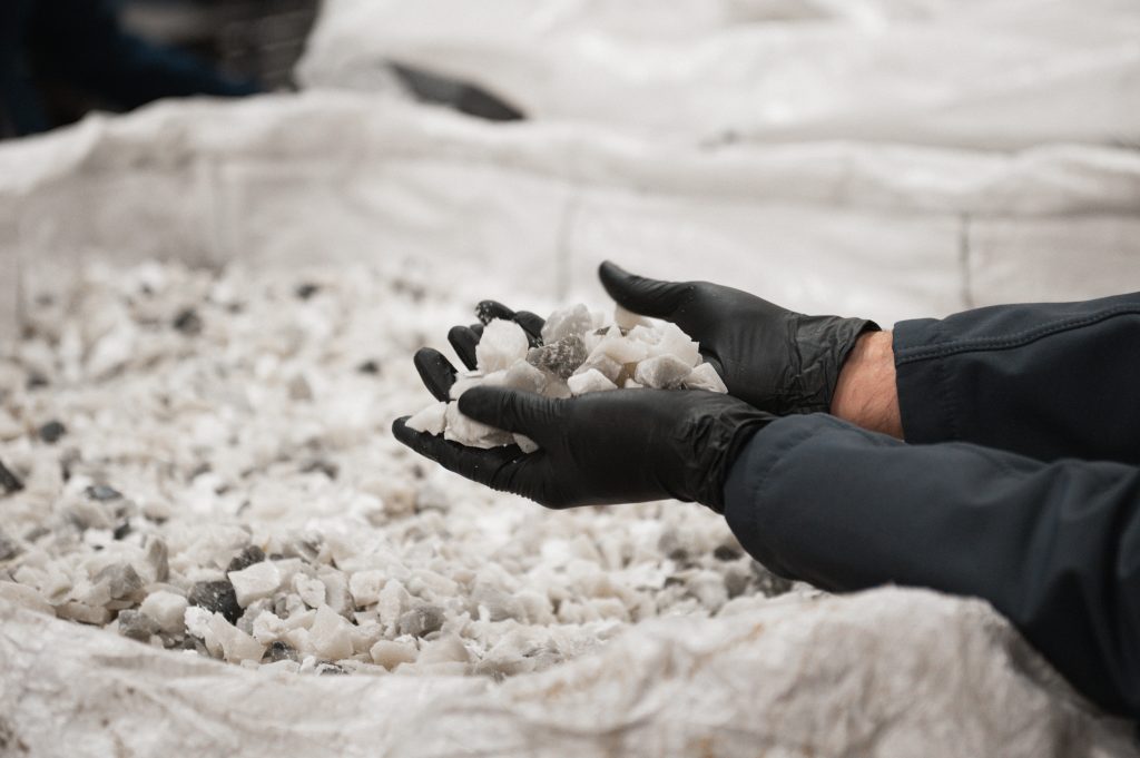 A person with gloves holding feedstock in a chemical recycling facility in Tigard, Oregon.