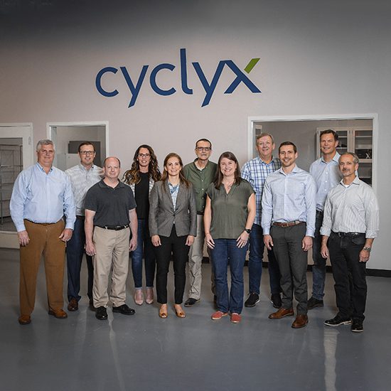 Cyclyx employees standing in front of the Cyclyx logo sign